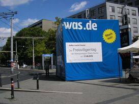 Vor dem Mannheimer Hauptbahnhof wirbt der Blaue Würfel für den Freiwilligentag der Region.